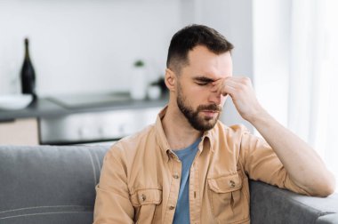 Kafkas sakallı yorgun adam koltukta oturuyor ve başı ağrıyor. Sağlıksız bir adam soğuk algınlığına yakalanır veya grip olur, hastalığa üzülür, mutsuz bir adam depresyona girer.