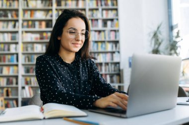 İş yerindeki çekici kadın programcı. Laptop kullanan güzel bir kadın, yeni bir proje ya da uygulama geliştiriyor, modern ofiste masaya oturuyor, gülümsüyor.