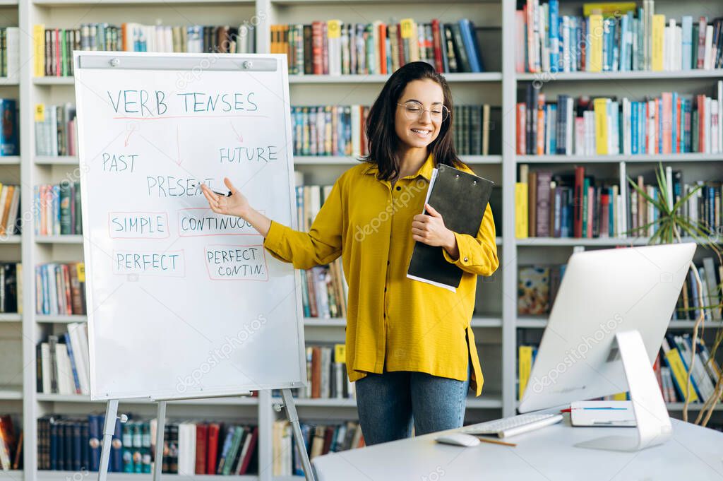 Caucasian young stylish female tutor or stands near flipchart, conducts an online presentation by video conference, online lesson concept