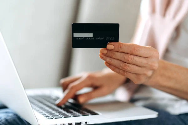 Credit card in a female hand. Shopping online, paying online, using a credit card and laptop to pay online