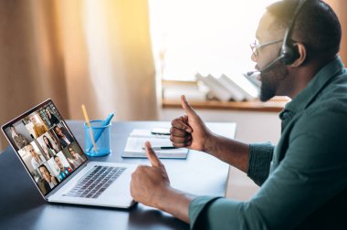 Başarılı bir Afrikalı Amerikalı, video konferansında bilgisayar kullanarak iş arkadaşlarıyla çevrimiçi video iletişimi için bir uygulama kullanıyor. Grup beyin fırtınası, webinar, online konferans