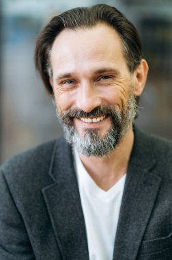 Resmi şık takım elbiseli, neşeli, gri saçlı, olgun iş adamının portresi. Mutlu başarılı girişimci dostça gülümseyerek doğrudan kameraya bakıyor.