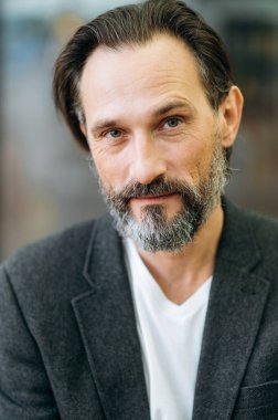 Modaya uygun giyinmiş olgun nüfuzlu bir erkeğin yakın plan portresi. Ciddi gri saçlı işadamı doğrudan kameraya bakıyor, özgüven ve başarı gösteriyor.