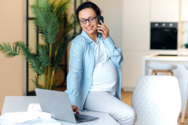 İş yerinde hamile bir kadın karışık ırk yetişkin mutlu bir bilgisayar.