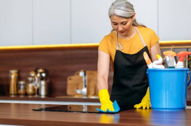 Asyalı temizlikçi, önlük, deterjan, ocak, mutfak, kova, gülümseme.