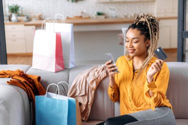 Afrikalı Amerikalı güzel bir kadın online kredi kartı alışverişi yapıyor.