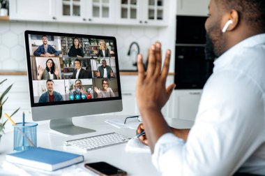 Video görüşmesi, online konferans. Çok uluslu iş adamları grubuyla bilgisayar ekranındaki Afrikalı Amerikalı adamın omuz üstü görüntüsü, sanal iş toplantısı, ev kavramından çalışma