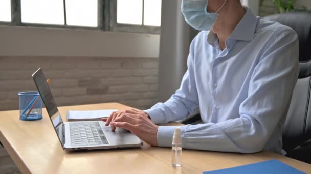 Caucasian man, office worker or manager, in a medical mask, sits at workplace, in formal wear, disinfects his hands with antiseptic during work, does prophylaxis, takes care of his health, precautions — 图库视频影像