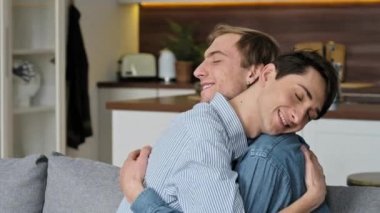 Lgbt 'nin adamları. Sevgi dolu eşcinsel çift, evde oturuyor, şefkatle sarılıyor ve birbirlerini okşuyor, oturma odasındaki kanepede birlikte dinleniyorlar, birlikte vakit geçiriyorlar, eşcinsel çiftler.