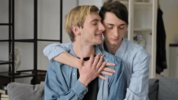 Relação entre pessoas do mesmo sexo, conceito lgbt. Um casal gay amoroso passa o tempo juntos em casa no sofá, eles se abraçam e acariciam uns aos outros, estão felizes por estarem juntos — Vídeo de Stock