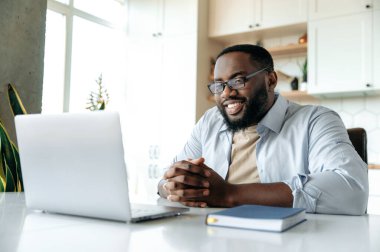 Yakışıklı, kendinden emin, Afro-Amerikan sakallı, gözlüklü, resmi tişörtlü iş adamı, menajer ya da komisyoncu.