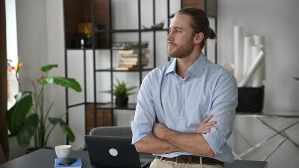 Guapo seguro de sí mismo atractivo caucásico elegante vestido chico, diseñador, freelancer o empleado, de pie cerca de su escritorio, con los brazos cruzados, mirando a la cámara y sonriendo amigable — Vídeos de Stock