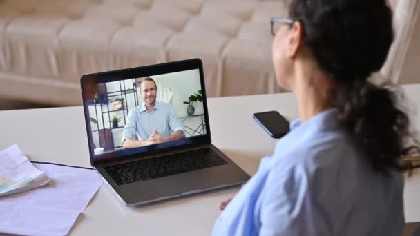 Videoconferencia, lluvia de ideas. Ver por encima del hombro de una mujer de negocios a una pantalla de computadora portátil con un colega amigable, compañeros de trabajo charlando usando una aplicación de comunicación en línea, reunión en línea — Vídeo de stock