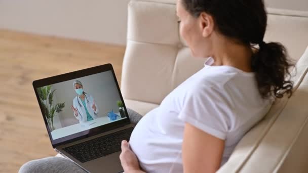 Distance medical help, online medical consultation. Pregnant woman talks with a female doctor by video call uses laptop, getting medical consultation, receives answers to questions and recommendations — Stock Video