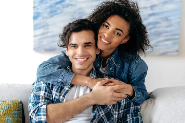 Retrato de una feliz pareja de mestizos enamorados. Chica rizada americana bastante africana y chico atractivo hispano tiernamente abrazándose, mirando a la cámara, sonriendo, familia feliz — Foto de Stock