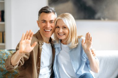 Sanal video toplantısı. Arkadaş canlısı, neşeli, olgun, Kafkasyalı, şık giyinmiş, arkadaşlarıyla görüntülü konuşma, el hareketlerini hoş karşılama, kameraya bakma, gülümseme.