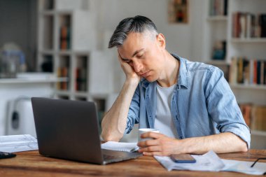 Uykulu, yorgun, çekici, beyaz saçlı üst düzey yönetici, serbest çalışan ya da ofis çalışanı, gündelik giysiler içinde, iş sırasında bir dizüstü bilgisayarın arkasında uyuyakalmış, işe ara vermiş, dinlenmeye ihtiyacı varmış.