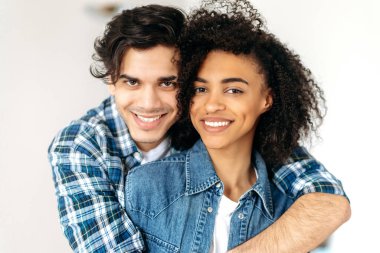 Güzel, genç, melez bir çiftin yakın plan portresi. Çekici, İspanyol bir erkek. Afrikalı, kıvırcık saçlı güzel kızına nazikçe sarılıyor.