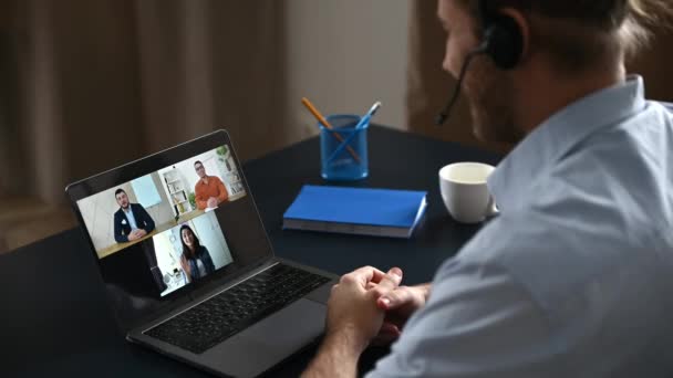 Ομαδική καταιγίδα ιδεών, online βίντεο συνάντηση με συναδέλφους. Καυκάσιος άντρας επικοινωνεί με συνεργάτες μέσω βιντεοκλήσης χρησιμοποιεί φορητό υπολογιστή. Προβολή πάνω από τον ώμο σε μια οθόνη laptop με επιχειρηματίες — Αρχείο Βίντεο