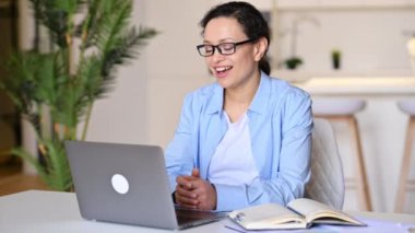 Tatmin olmuş, başarılı, melez, stil sahibi iş kadını, yönetici, gözlüklü, uzaktan çalışan, iş arkadaşı veya müşterisiyle çevrimiçi görüşmeler yapan, eliyle hareket eden, arkadaşça gülümseyen