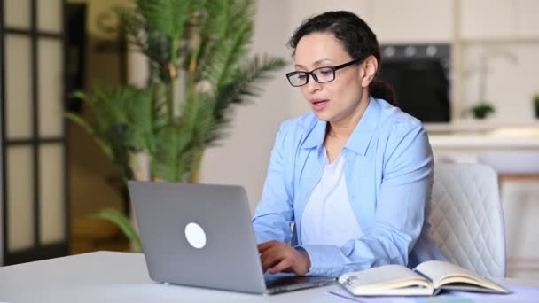 Fatiga, mujer madura de raza mixta estresante, mujer de negocios inteligente, trabajando remotamente, se sienta en el escritorio, descansando, teniendo dolor de cabeza, sosteniendo gafas en la mano, ojos cerrados, necesita descansar — Vídeo de stock