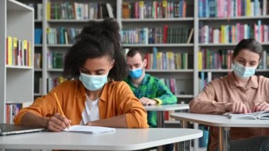 Koruyucu tıp maskeli çok ırklı öğrenciler konferans sırasında kütüphanede güvenli bir mesafede masalarda otururlar. Zeki Afrikalı Amerikalı bir kız not alır, kafasını çevirir ve hafta sonunu düşünür.