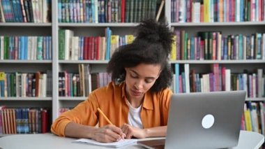 Zeki Afro-Amerikan bayan öğrenci bir derste oturuyor, bir sorunun cevabını biliyor, elini kaldırıyor, cevap vermek istiyor, kameraya bakıyor, gülümsüyor, bilgi ve eğitim kavramına bakıyor.