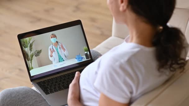 Distans medicinsk hjälp, online medicinsk konsultation. Gravid kvinna samtal med en kvinnlig läkare genom videosamtal använder laptop, få medicinsk konsultation, får svar på frågor och rekommendationer — Stockvideo