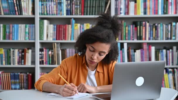 Excelente alumna. Chica estudiante afroamericana inteligente en una conferencia se sienta en una mesa, con estilo vestido, levanta la mano, sabe la respuesta a la pregunta y tiene una idea, quiere responder, sonríe — Vídeos de Stock