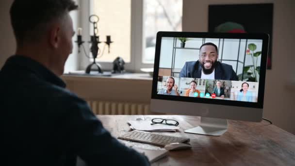 Información de negocios en línea. El hombre exitoso se comunica con compañeros de trabajo a través de videollamadas utiliza la aplicación y el ordenador, sentado en su escritorio, en la pantalla de la computadora muchos empresarios diferentes — Vídeo de stock