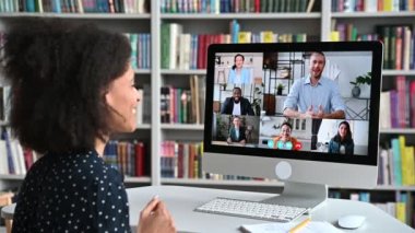 Video iletişimi, online konferans. Farklı iş adamlarıyla bilgisayar ekranındaki Afrikalı Amerikalı bir kadının omzunun üzerinden iş stratejisini tartışmak için bir video konferansında toplandı.