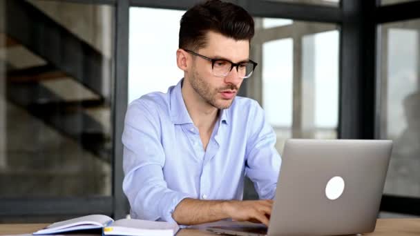 Zaskoczony zszokowany biały pracownik biurowy lub przedsiębiorca siedzi w miejscu pracy, zdumiony patrząc na laptopa, podnosząc okulary, otrzymał nieoczekiwane wieści, odniósł zwycięstwo, otrzymał duży zysk — Wideo stockowe