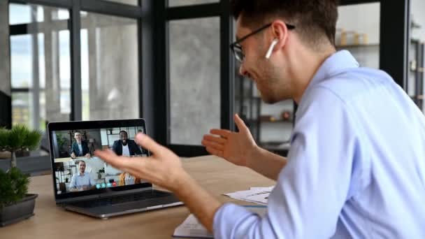 Videoconferencia de lluvia de ideas, reunión de negocios en línea. El hombre de negocios exitoso, hablando en videollamada con colegas, utilizando el ordenador portátil mientras está sentado en la mesa de trabajo en la oficina, discutir la estrategia de negocios — Vídeo de stock