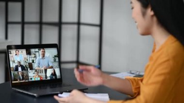Video görüşmesi, çevrimiçi konferans, uzaktan görüşme. Çinli kız, öğrenci ya da serbest çalışan, çevrimiçi bir ders izliyor, notlar alıyor, bilgisayar ekranında çok ırklı gülümseyen insanlar.
