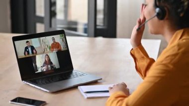 İnternetteki iş grubunun video konferansından beyin fırtınası. Tatmin olmuş Afrikalı Amerikalı genç bir kadın, iş ortaklarıyla video bağlantısı kuruyor, bilgisayarını kullanıyor, bilgisayardaki başarılı iş arkadaşlarını kullanıyor.