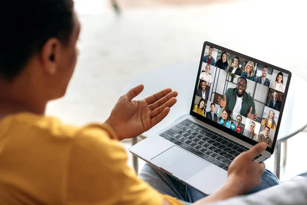 Comunicação à distância usando aplicativo e laptop. O cara se senta no sofá, usa um laptop para se comunicar com colegas ou amigos via videoconferência, reunião virtual, conceito de telecomunicações — Fotografia de Stock