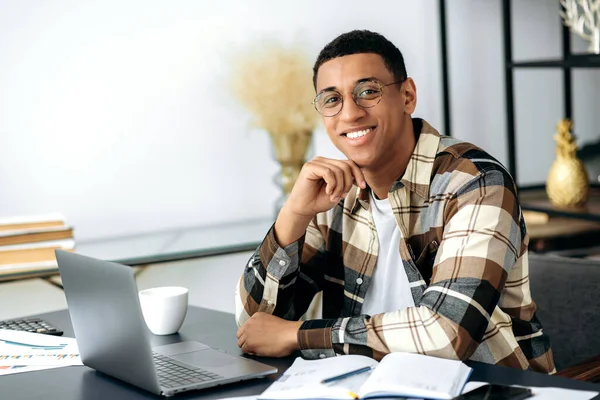 자신감 있는 젊은 혼합 인종 라티 노 남자, 프리랜서 또는 매니저 셔츠와 안경을 착용하고 책상에 앉아 — 스톡 사진