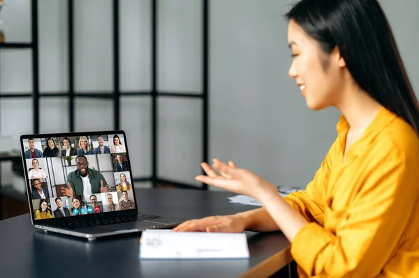 Online business meeting, brainstorm of employees. Asian successful young woman talking on video conference with colleagues of different nationalities, discussing the project. Online conversation