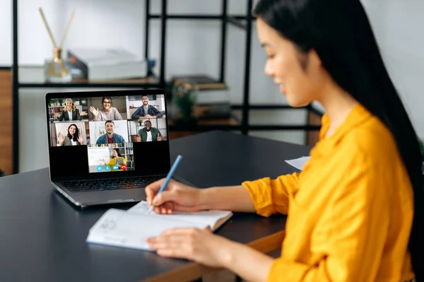 Educação online. Menina estudante japonês inteligente ganha conhecimento assistindo aula on-line e aprender distantemente. Jovem toma notas durante webinar, ouvindo palestra de professora sobre videochamada — Fotografia de Stock