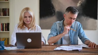 İş adamı ve iş kadını şık kıyafetler içinde masada oturuyor, yeni bir proje üzerinde çalışıyor, belgeleri inceliyor ve kontrol ediyor, başarı anlaşması yapıyor, birbirlerine beş tane veriyorlar, gülümsüyorlar, seviniyorlar.