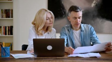 İki başarılı orta yaşlı Kafkas iş ortağı gündelik giysiler içinde masada oturmuş fikir ve stratejileri tartışıyorlar, belgelere bakıp gülümsüyorlar.