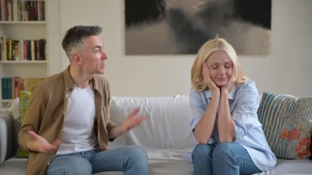 Misunderstanding, family quarrel. Upset, indignant gray-haired husband is emotionally talking and looking at his wife, gesturing with his hands, wife is upset because of a dialog, experiencing stress — Stock Video