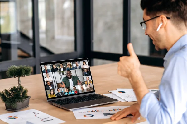 Мозговой штурм, видео брифинг. Кавказский мужчина проводит виртуальную онлайн-встречу через видео-конференцию с успешными многорасовыми коллегами, используя ноутбук, сидит в офисе, планируя маркетинговую стратегию и идеи — стоковое фото