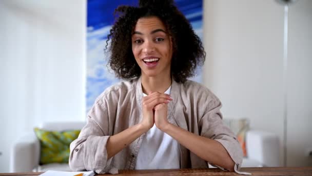 Positieve vriendelijke jonge Afrikaanse amerikaanse krullende vrouw, student of freelancer, werken of studeren op afstand, praten op video conferentie met collega 's of vrienden, gebaren met de handen, glimlachen — Stockvideo