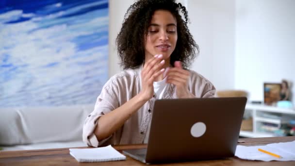 Positiv selbstbewusste Afroamerikanerin, Studentin oder Freiberuflerin, die aus der Ferne arbeitet oder studiert, mit Kollegen oder Freunden per Laptop telefoniert, mit Händen gestikuliert, lächelt. Videoanruf — Stockvideo