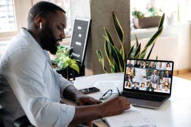 Çevrimiçi iş semineri. Çevrimiçi finans dersinde not alan Afrikalı bir Amerikalının omzunun üzerinden bakıldığında, dizüstü bilgisayar ekranında, çok ırklı iş arkadaşları vardır.