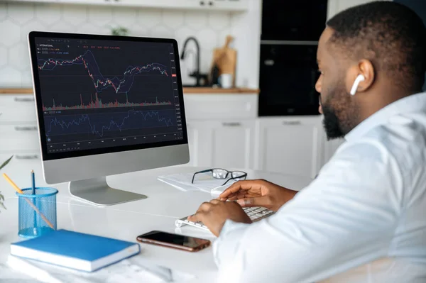 Investeringen, handel op de beurs. Afro-Amerikaanse man handelaar investeerder, analyseert cryptogeld financiële markt, kijkt naar de computer, trading data index grafiek op pc scherm — Stockfoto