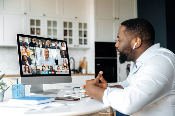 Μακρινή συνάντηση, διαδικτυακή επικοινωνία. Αφροαμερικάνος επιχειρηματίας έχει μια εικονική συνάντηση με πολυφυλετικούς συναδέλφους των επιχειρήσεων, συζητώντας την οικονομική στρατηγική, μιλώντας σε μια βιντεοκλήση, brainstorming — Φωτογραφία Αρχείου