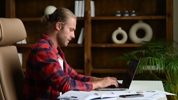 Americano con estilo freelancer exitoso, estudiante o gerente, vestido con estilo, se sienta en el escritorio de trabajo, terminar el trabajo, cerca de la computadora portátil, fin del día de trabajo, tener un descanso — Vídeos de Stock