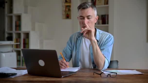 Pensativo exitoso inteligente de pelo gris senior caucásico hombre de negocios, corredor o freelancer en ropa casual, trabaja de forma remota con un ordenador portátil, la planificación de un proyecto de negocio o informe, se le ocurrió una buena idea — Vídeos de Stock